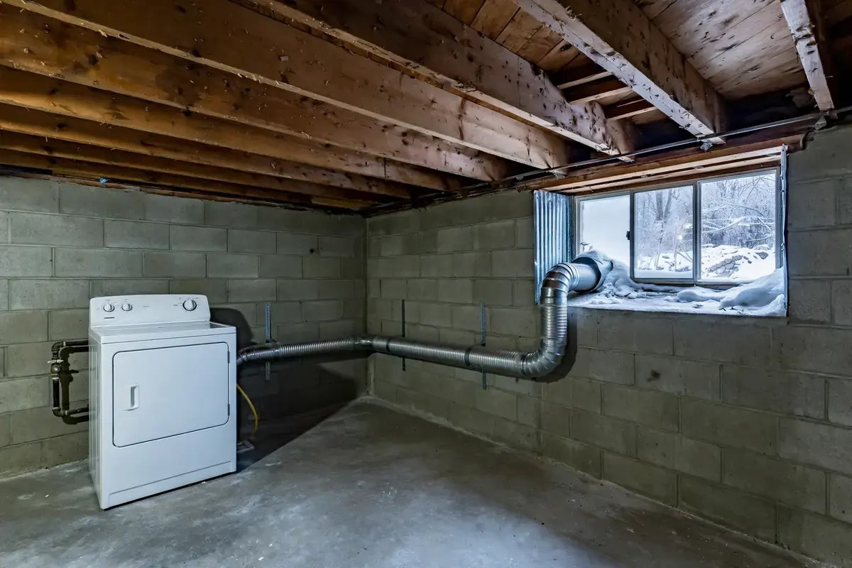 Basement laundry area with a dryer and exhaust duct running to an outside wall