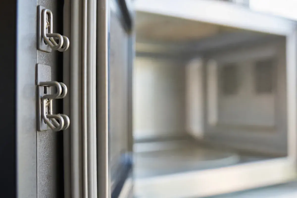 Microwave door latch hooks and the door seal edge